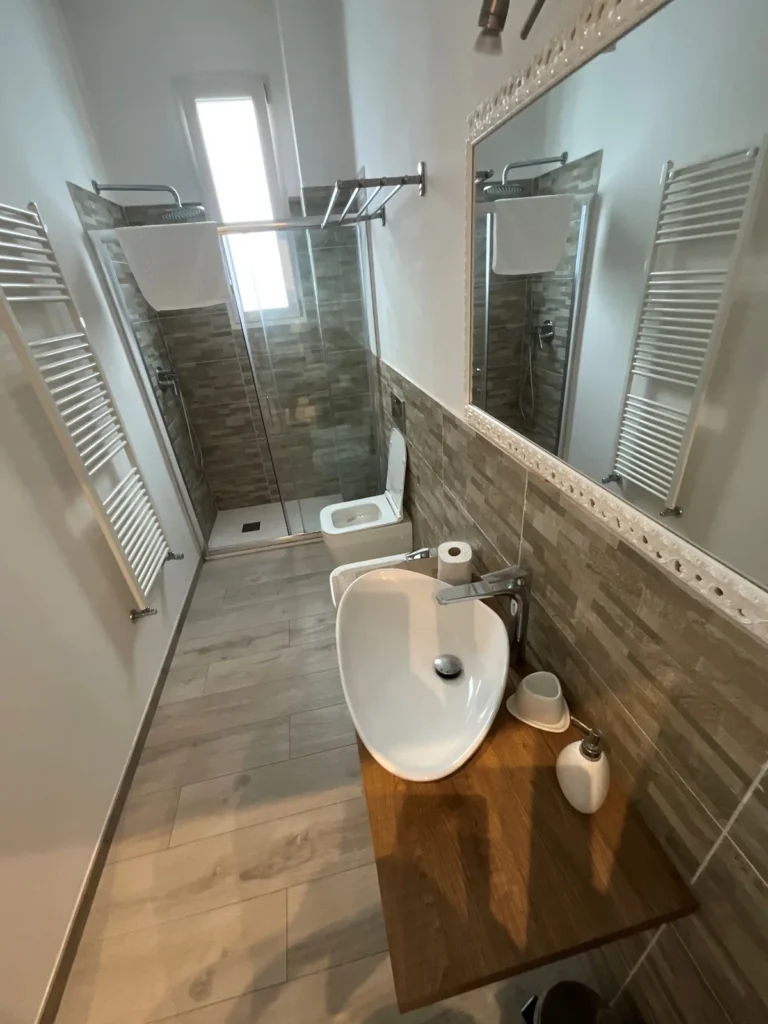 Bagno con doccia in vetro, lavabo, bidet e scaldasalviette