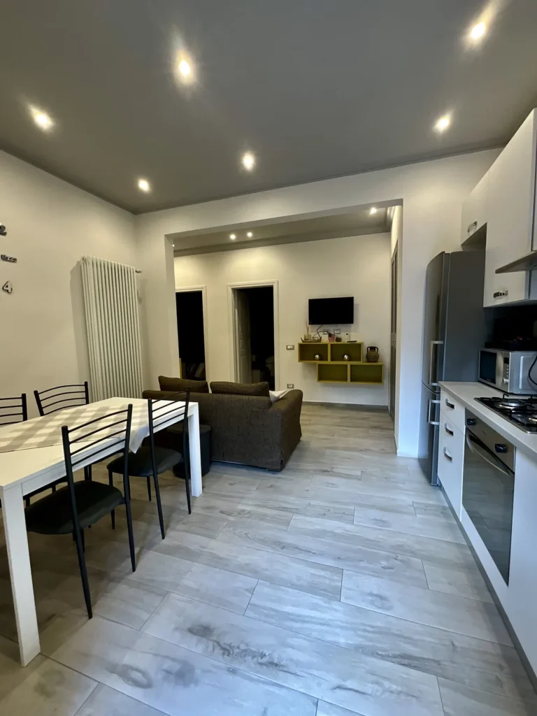 Cucina e zona pranzo con vista sul salotto e sulla TV a parete
