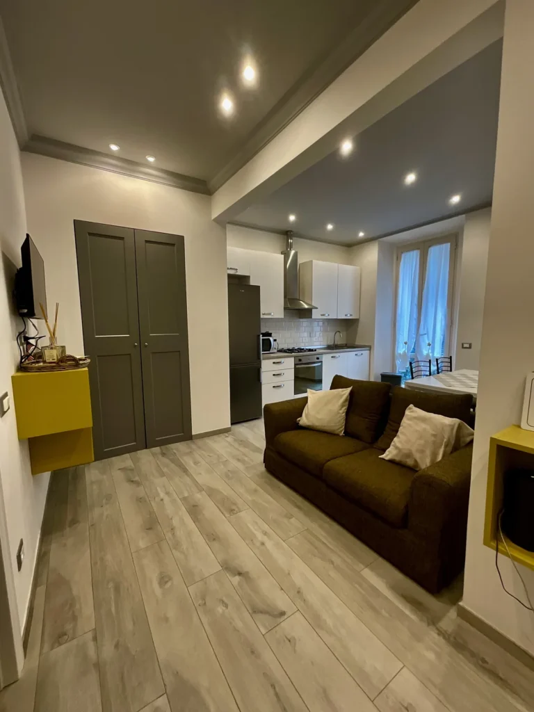 Salotto con divano marrone e cucina a vista di Tommy House