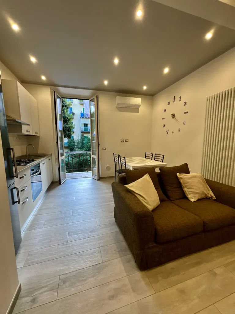Zona giorno con divano, tavolo da pranzo e porta aperta sulla terrazza
